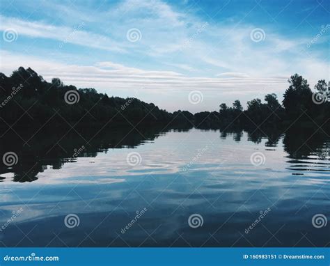 Beautiful Blue River With Reflecting Clouds In The Water In The Middle