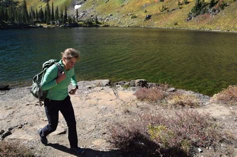 A Woman With A Backpack Is Walking On The Edge Of A Cliff Near A Lake