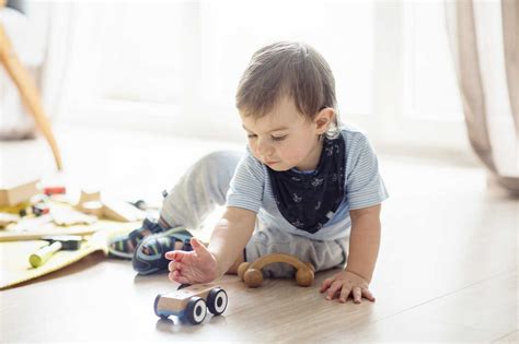 Baby Boy Playing With Toys While Sitting On Floor At Home Stock Photo