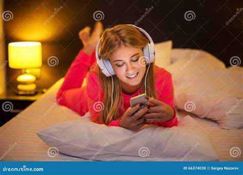 Young Women Listening To The Music From Smartphone On Bed Stock Photo