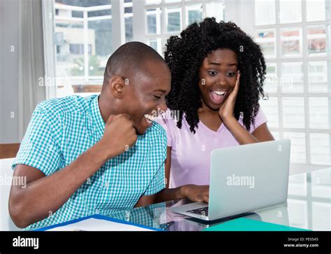 african american couple shopping presents and ts online with laptop at desk at home stock