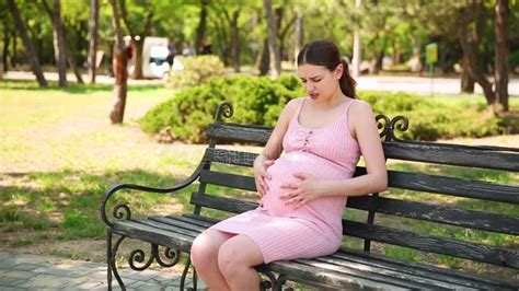 A Pregnant Girl Is Standing In The Park And Her Stomach Begins To Hurt