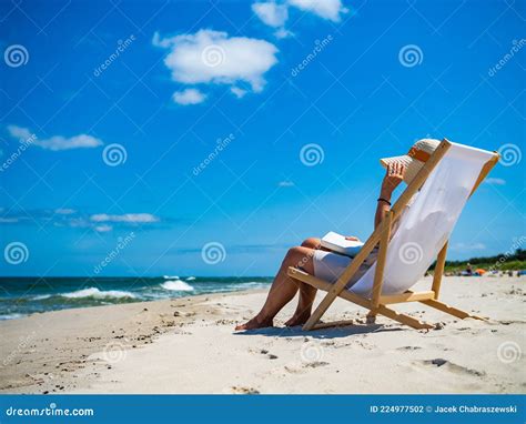 Woman Relaxing On Beach Reading Book Sitting On Sunbed Stock Photo