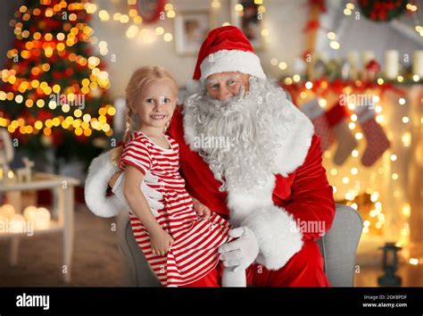 Little Girl Sitting On Santas Lap In Room With Beautiful Christmas