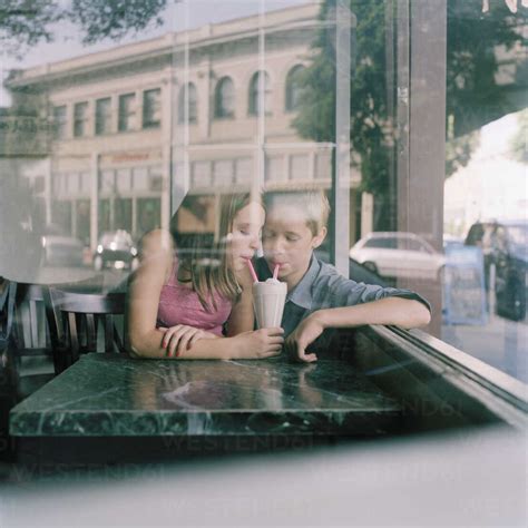 A Young Teenage Couple Sharing A Milkshake At A Diner Viewed Through