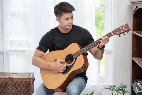 Free Photo A Man Sitting And Playing Guitar On A Chair