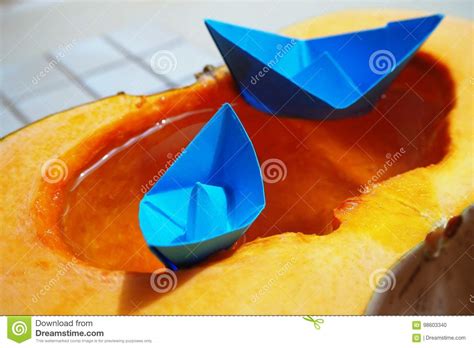 Blue Origami Paper Boat Sailing On Water In Orange Pumpkin Stock Photo