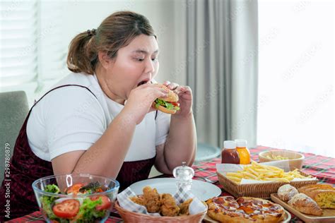 Asian Fat Girl Hungry And Eat A Junk Food On The Table Stock Photo