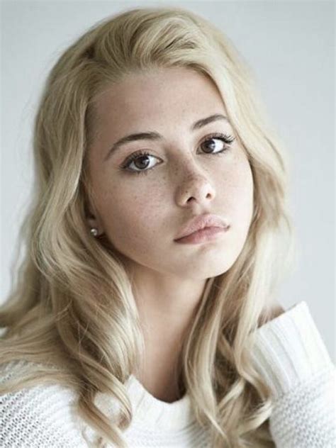 A Woman With Long Blonde Hair Wearing A White Sweater And Looking Off