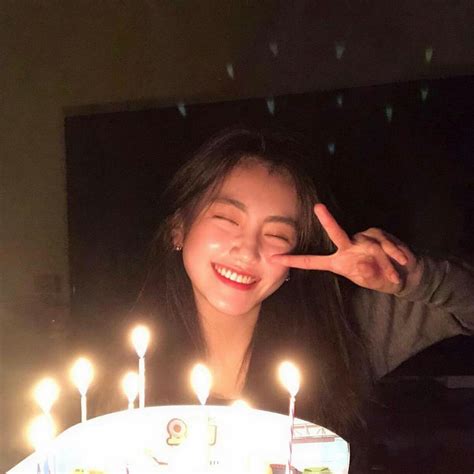 A Woman Smiles As She Holds Her Hand Up In Front Of A Birthday Cake