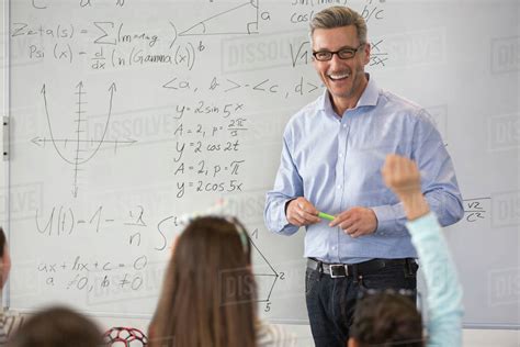 Smiling Male Science Teacher Leading Lesson At Whiteboard In Classroom