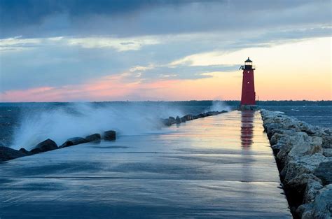 A Colorful Sunset And Waves Splashing At The Manistique Lighthouse
