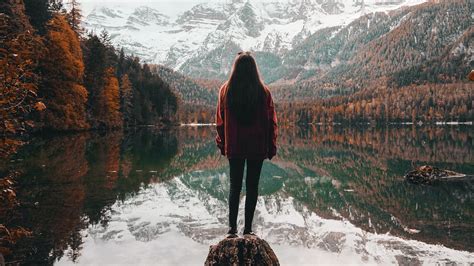 Girl Is Standing Alone On Rock Stone Near Lake With Reflection Of