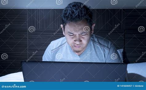 Tired Sleepy Man Working On Laptop Untill Midnight On Bed Stock Image
