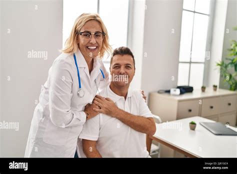 Middle Age Man And Woman Doctor And Patient Hugging Each Other Having Medical Consultation At