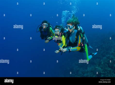 Three Scuba Divers Mother And Daughters Diving Over A Coral Reef