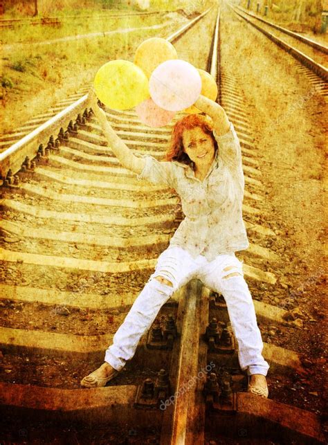 Hermosa pelirroja cumpleaños chica sentada con globos de colores en el ferrocarril