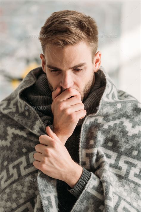 Sick Man Wrapped In Blanket Coughing While Covering Mouth With Hand