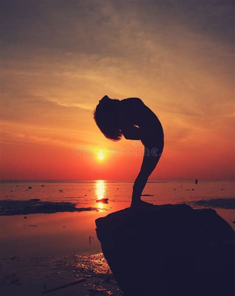 Silhouette Yoga Girl By The Beach At Sunrise Doing Standing Pose Stock