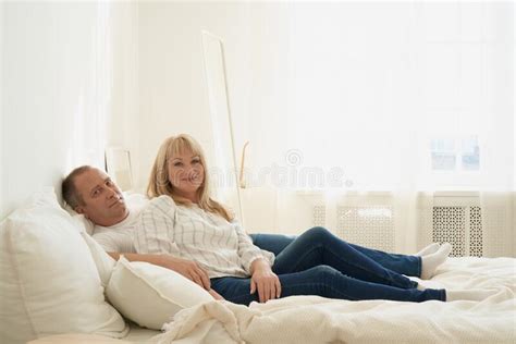 Full Lenght Portrait Of Mature Couple In Home Interior On Sofa Stock