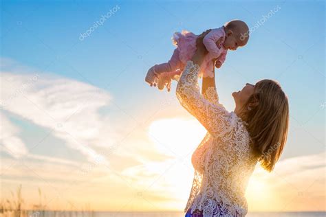 Happy Mother Holding Her Cute Baby At Sunset — Stock Photo © Grinvalds
