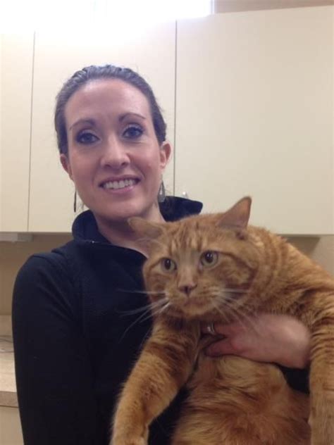 A Woman Holding An Orange Cat In Her Arms And Smiling At The Camera