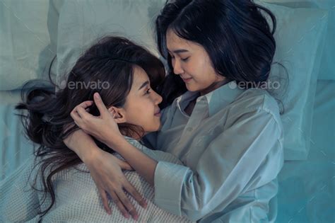 Attractive Asian Beautiful Lesbian Couple Lying Down In Pajamas On Bed And Hugging Each Other