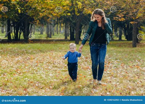 Portrait Of A Beautiful Young Mother With Her Son Walks In The Autumn