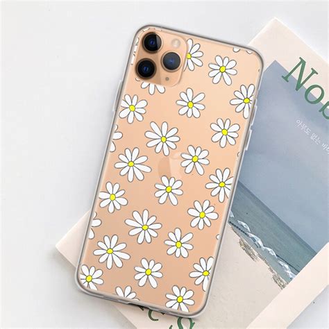 An Iphone Case With Daisies On It Next To A Magazine