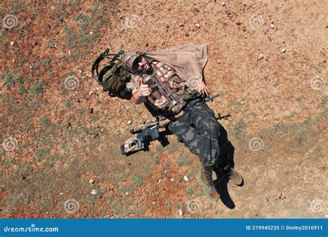 Top View A Soldier Sniper While Resting He Lies On The Red Hot Desert Ground And Rests Stock