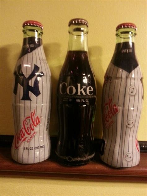Three Coca Cola Bottles Sitting On Top Of A Shelf