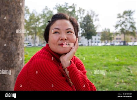 Outdoor Portrait Of A Middle Age Chinese Lady Sitting At The Public