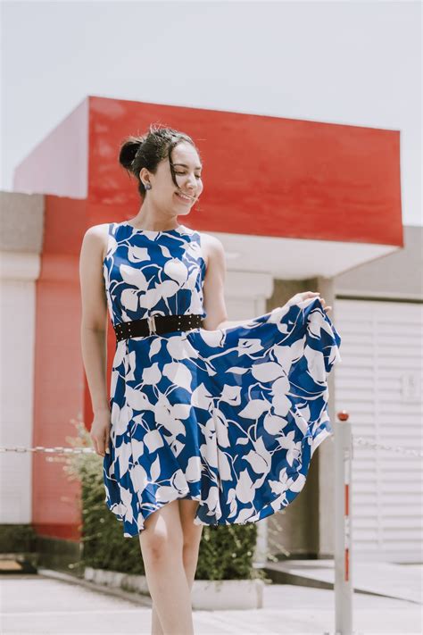 낮 동안 붉은 벽 근처에 서 있는 파란색과 흰색 꽃무늬 스파게티 스트랩 드레스를 입은 여자 사진 Unsplash의 무료 산토도밍고 이미지