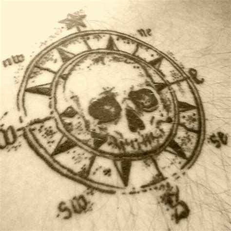 A Black And White Photo Of A Skull In A Compass Tattoo