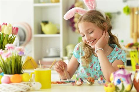 Portrait Of Beautiful Girl In Bunny Ears Painting Eggs For Easter