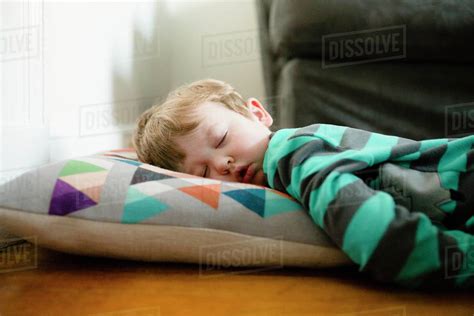 Tired boy sleeping on floor at home - Stock Photo - Dissolve