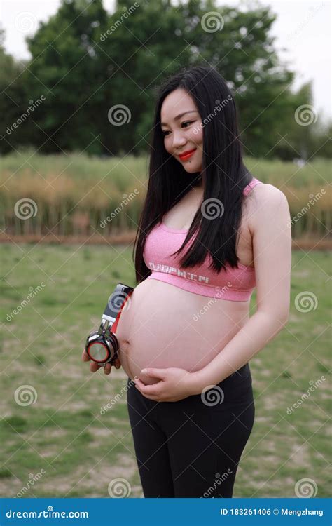 Asian Chinese Pregnant Woman In Yoga Dress Listen To Music Earphone On