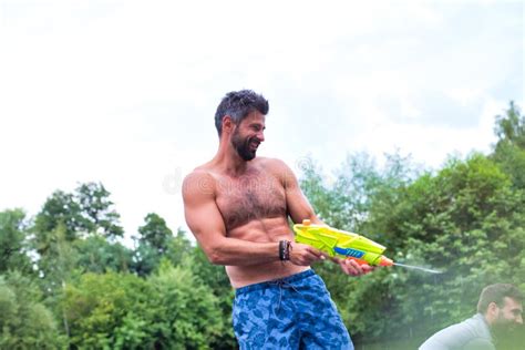 Cheerful Man Enjoying With Squirt Guns On Pier During Summer Stock