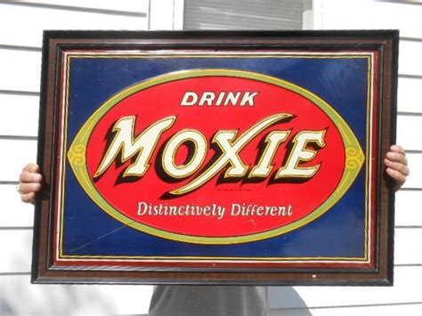A Man Holding Up A Framed Sign That Reads Drink Moxie Distinctively