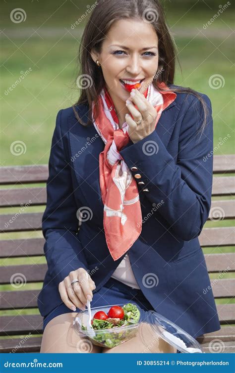 Portrait Of A Young Businesswoman Eating Salad While Sitting On Bench