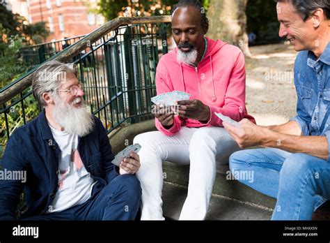 Three Mature Men Outdoors Sitting On Steps Playing Cards Stock Photo Alamy