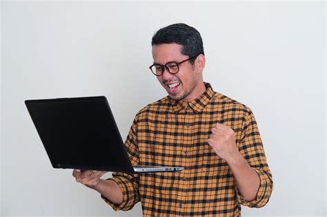 Premium Photo Adult Asian Man Clenching Fist Showing Excitement When Looking To His Laptop Screen
