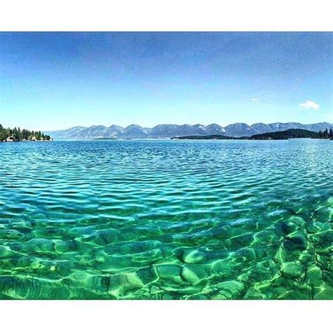 The Water Is Very Clear And Blue With Mountains In The Background