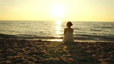 Woman Sitting On A Sand Beach In Front Of Sunset And Ocean In Summer Stock Footage Video 7596715