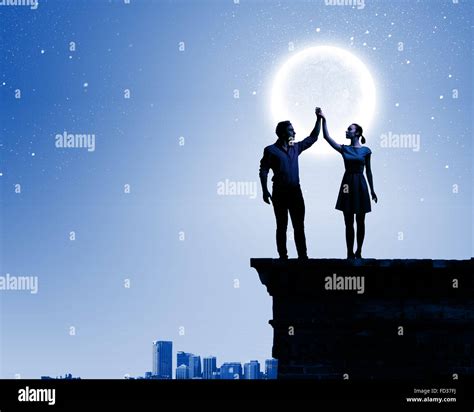 Silhouettes Of Young Romantic Couple Standing Under The Moon Light