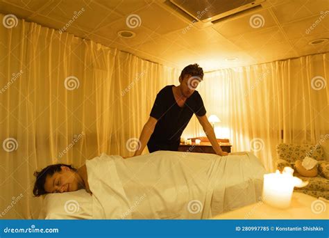 Massage Session Master Relaxes The Body Of The Female Client Through A White Cloth Stock Image