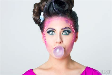 A Woman With Pink And Blue Makeup Blowing Bubble