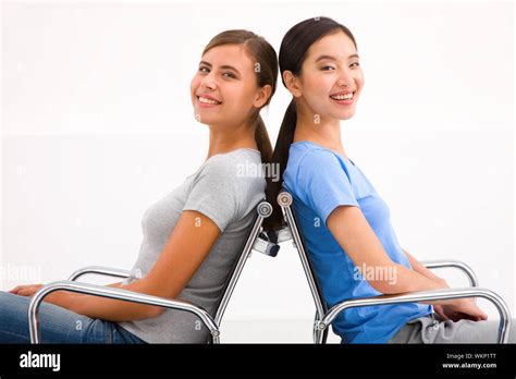 Two Happy Businesswoman Sitting In Chairs To Back Stock Photo Alamy