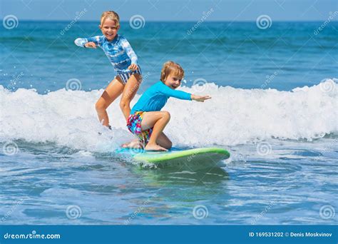 Two Young Surfers Ride With Fun On One Surfboard Stock Photo Image Of