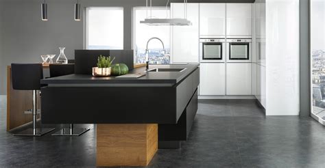 Cuisine noire et bois foncé avec grand îlot central toulouse.un pan de mur aménagé avec une colonne dédié au frigo et congélateur, une colonne pour le four intégré avec du rangement présent dans la partie haute et basse ainsi qu'une colonne de rangement sur le côté. Cuisine contemporaine : le plein d'idées pour l'aménager avec style